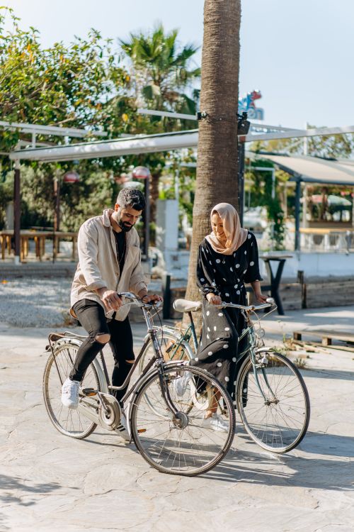 Free Man and woman riding bicycles leisurely in a sunny park with greenery. Stock Photo