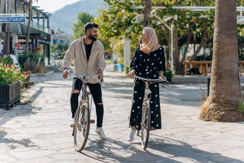 Free Smiling couple in a cheerful conversation while riding bicycles outdoors on a sunny day. Stock Photo