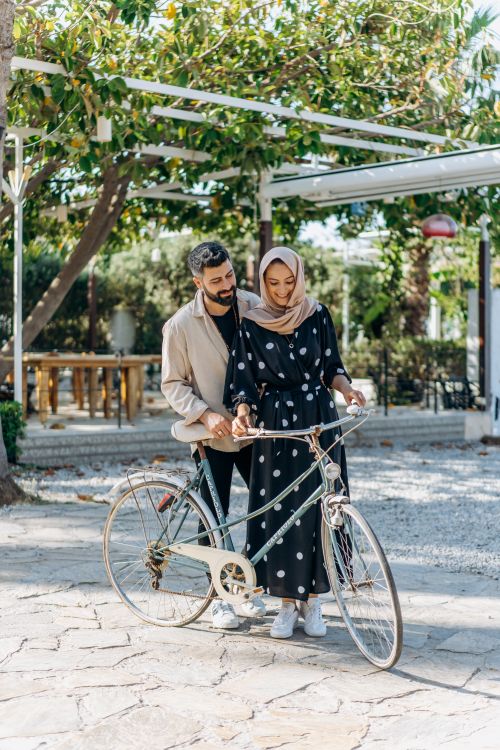 Free A couple enjoying a leisurely moment with a bicycle outdoors, embodying romance and happiness. Stock Photo
