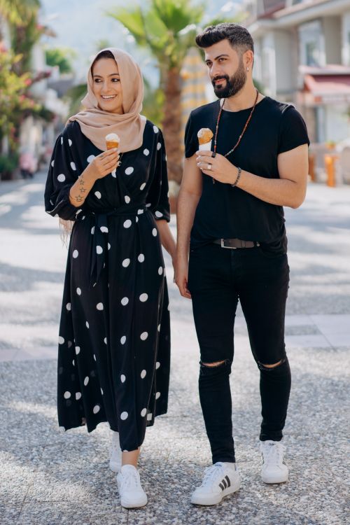 Free A stylish couple holds hands and enjoys ice cream on a sunny street, portraying happiness and connection. Stock Photo