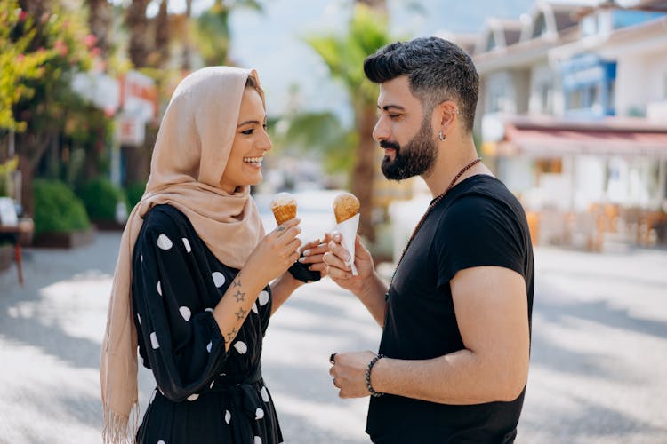 Man And Woman Standing Face To Face Holding Ice Cream In Cones