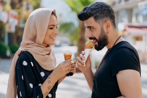 Free Smiling couple eating ice cream on a sunny day, showcasing affection and joy. Stock Photo