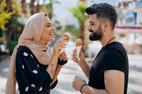 Free A joyful couple relishing ice cream cones outdoors in a sunny setting. Stock Photo