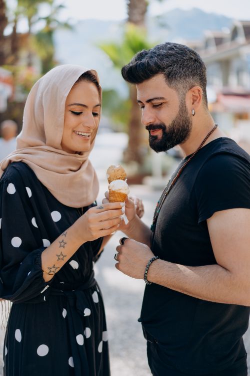 Free Smiling couple sharing ice cream on a sunny day, surrounded by lush greenery. Stock Photo