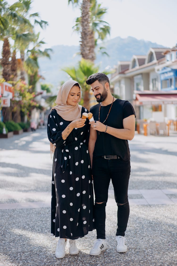 Man And Woman Standing Close To Each Other Holding Ice Cream In Cones