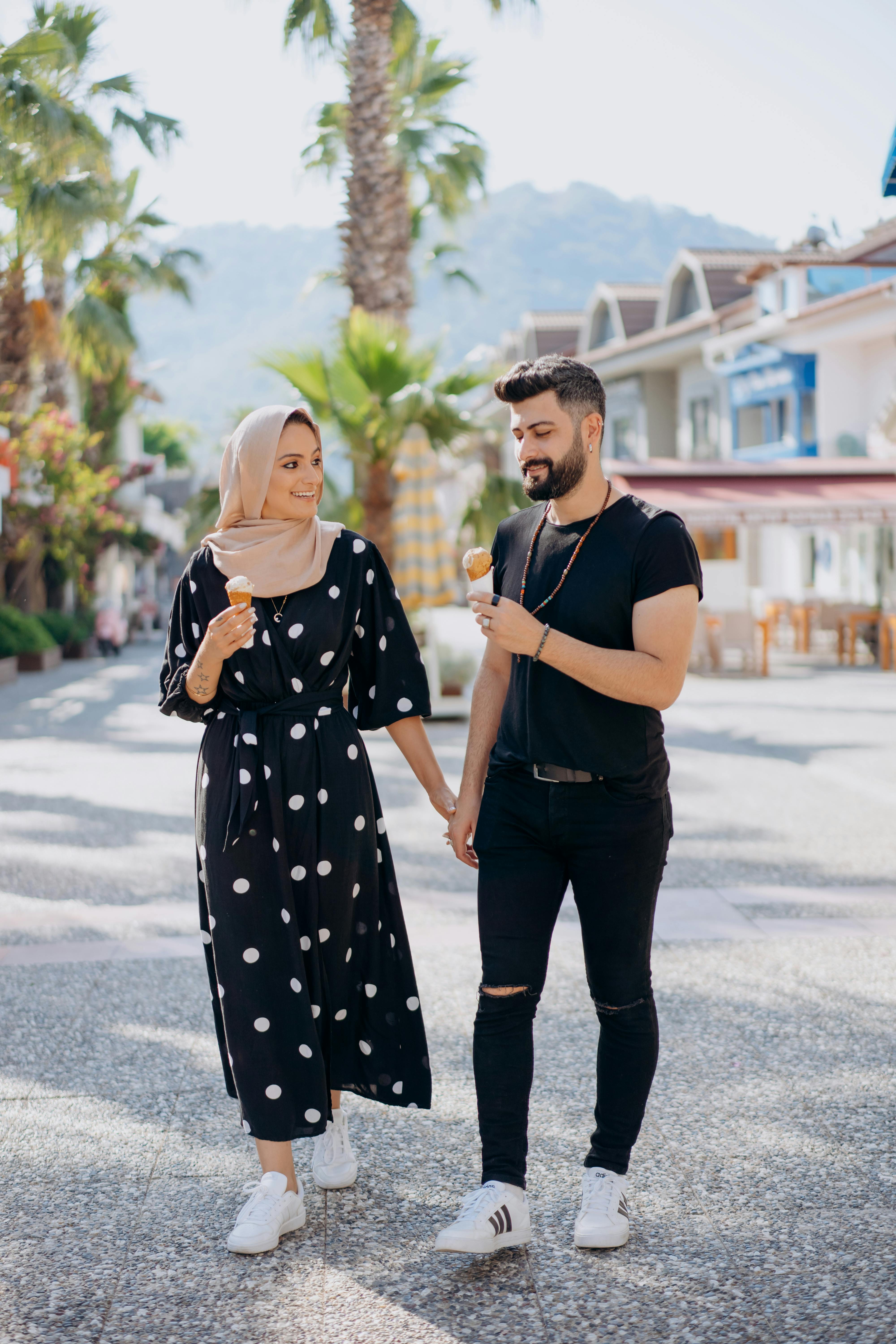 man and woman walking hand in hand with ice cream in cones