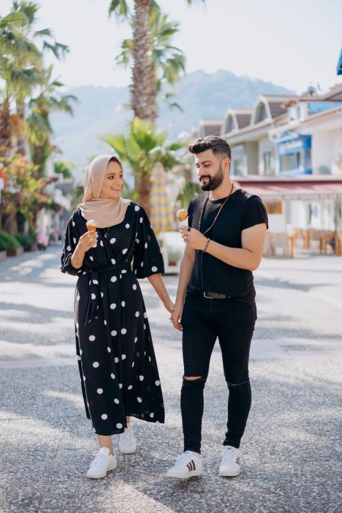 Free A loving couple enjoys a walk in a sunny outdoor setting, sharing ice cream and smiles. Stock Photo
