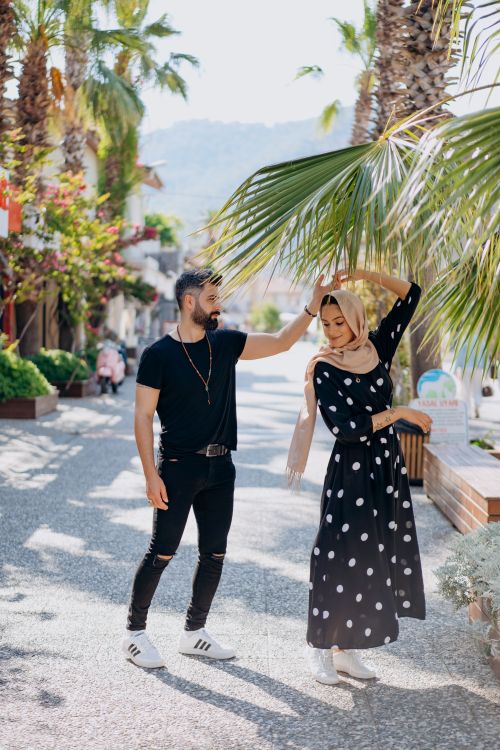 Free Romantic couple dancing outdoors, embracing love and fashion under sunny palm trees. Stock Photo