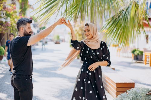 Free A fashionable couple joyfully dancing outdoors, showcasing love and style in a sunny setting. Stock Photo