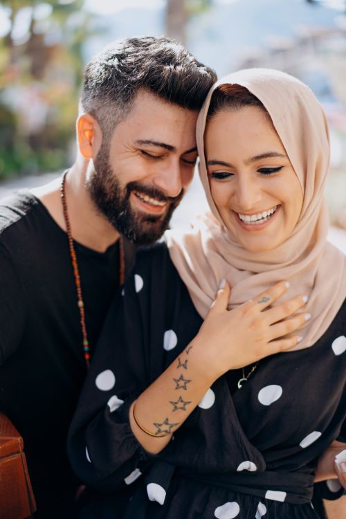 Free A joyful Middle Eastern couple sharing a moment of laughter and affection outdoors. Stock Photo