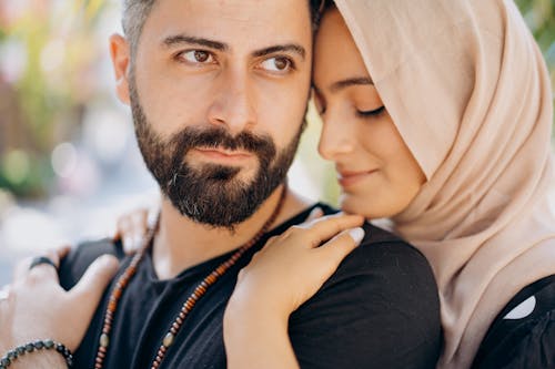 Free Woman Wearing Hijab Hugging a Bearded Man Stock Photo