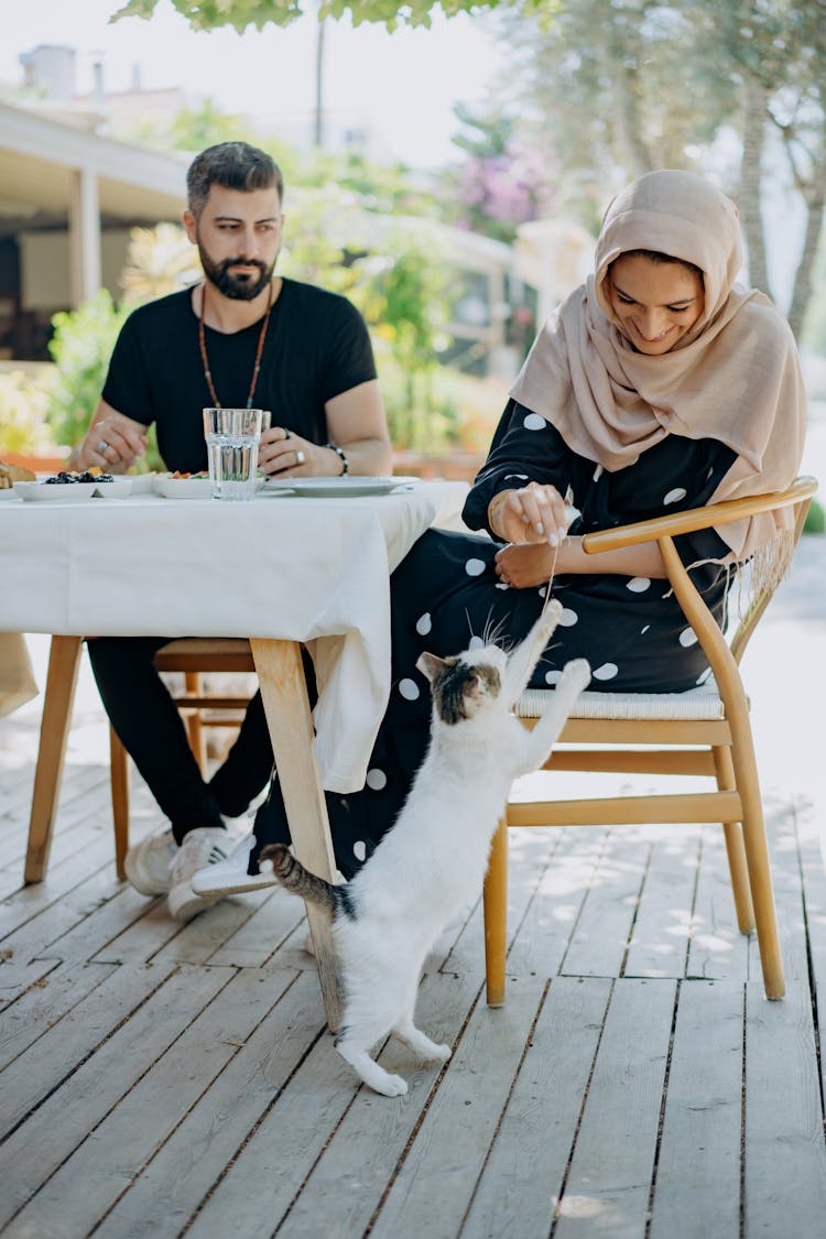 Woman Sitting By Table During Date Feeding Cat