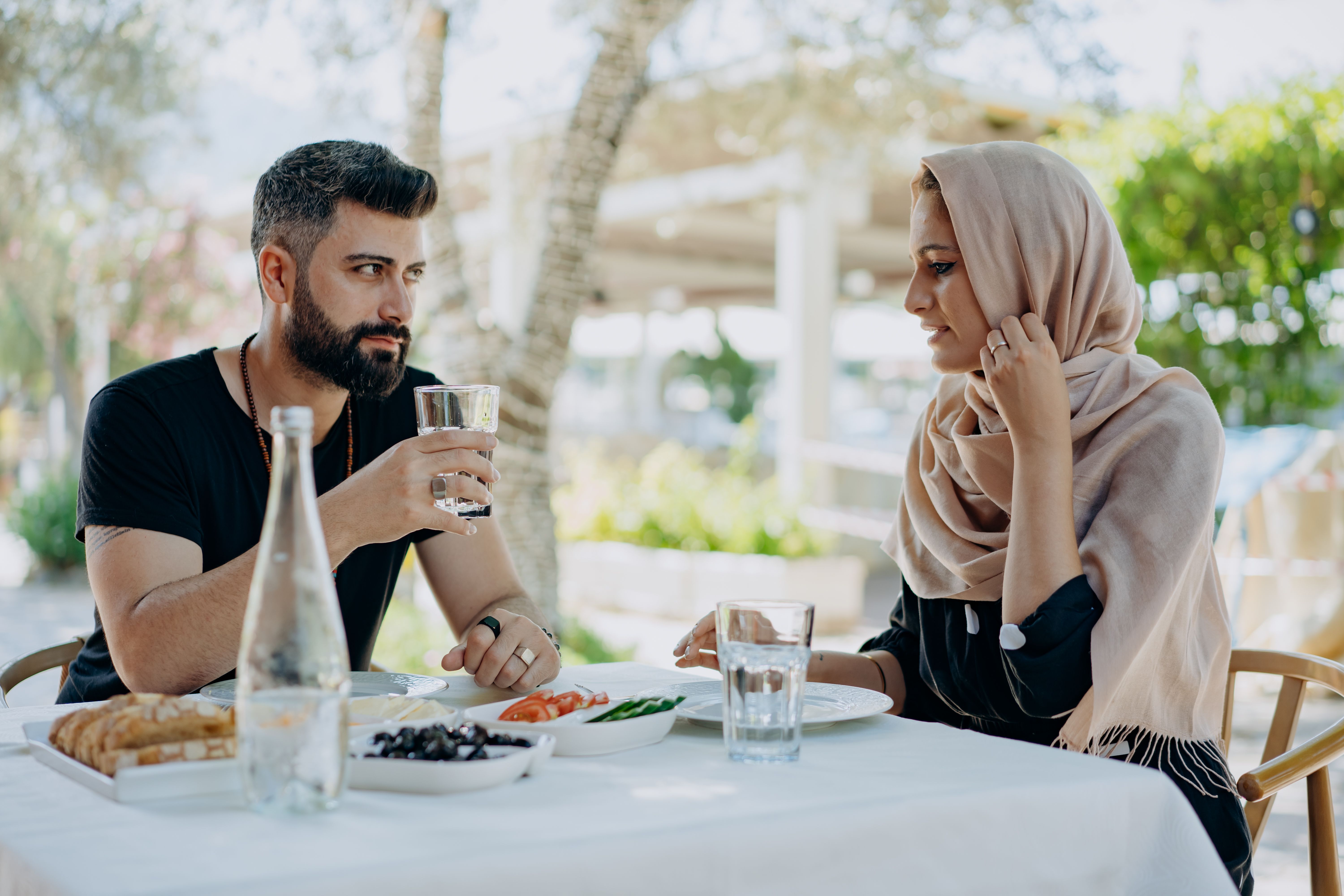 A couple shares a meal and conversation at an outdoor restaurant, capturing a warm and relaxed atmosphere.