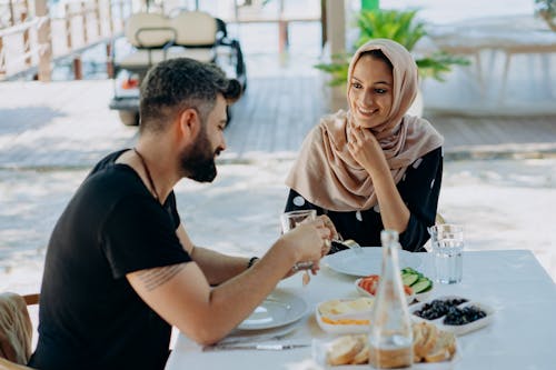 Free Man in Black Crew Neck T-shirt Sitting Beside Woman in Beige Hijab Stock Photo