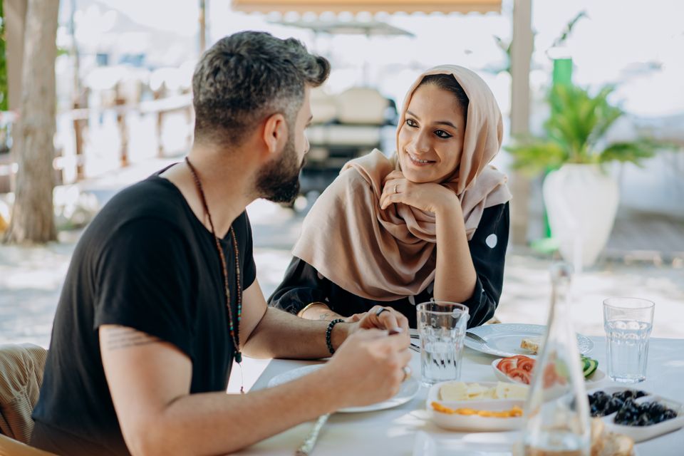 A couple smiling over lunch outdoors