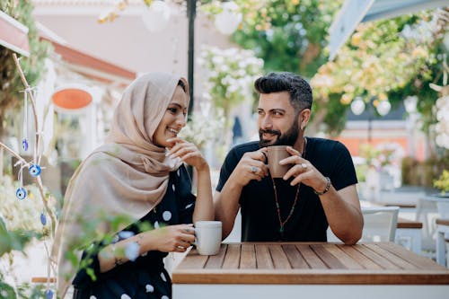 Man and Woman in Headscarf Drinking from Cups Outside