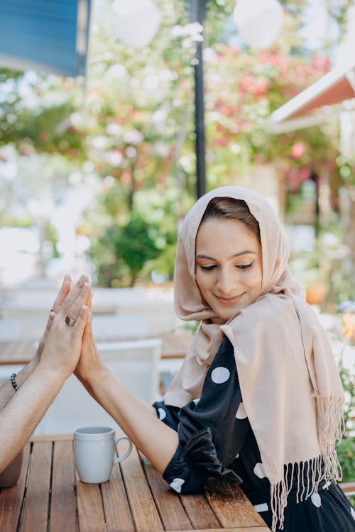 A Woman in a Headscarf with Her Hands Together with Another Person