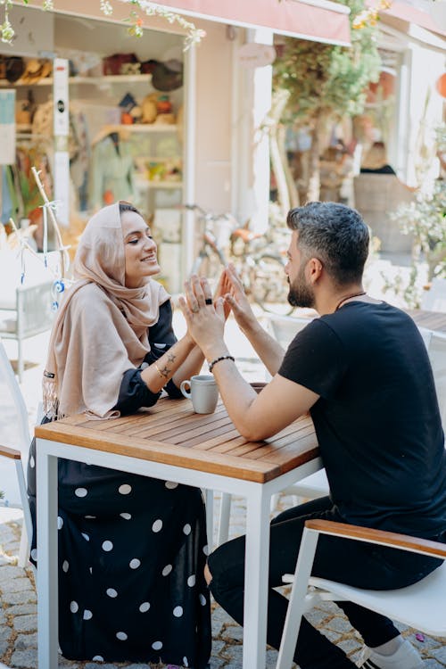 Free A Couple Touching Hands While Sitting and Having Coffee Stock Photo