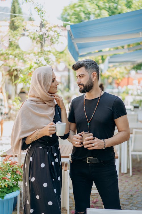 Free A Couple Standing While Holding Cups of Coffee Stock Photo