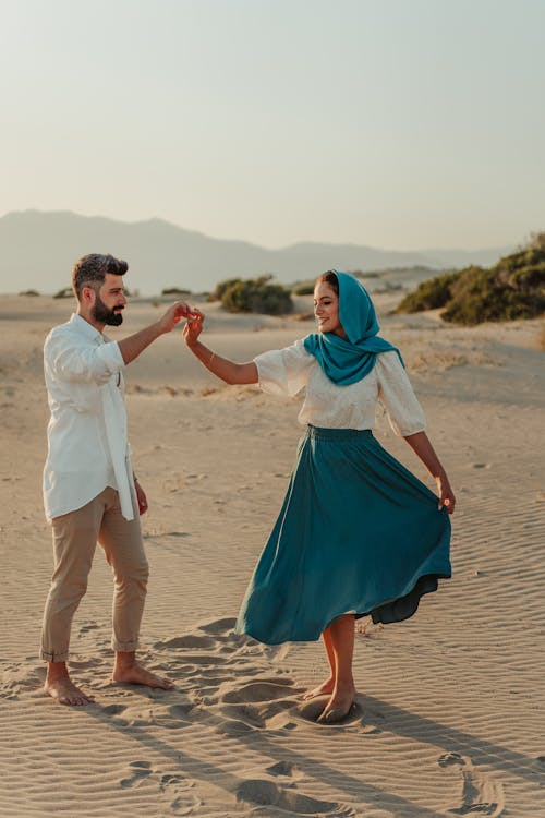 Free Man and Woman Holding Hands While Walking on Beach Stock Photo