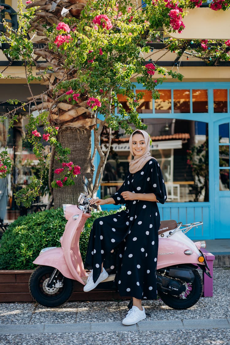 Side View Of A Woman In Hijab Sitting On The Scooter