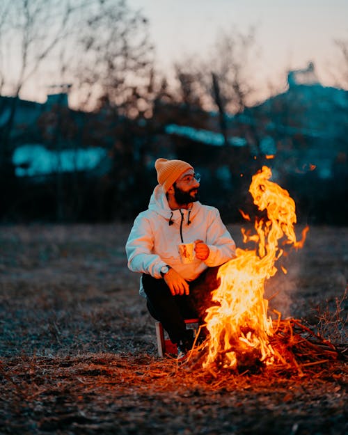 Man Relaxing in Front of a Burning Campfire