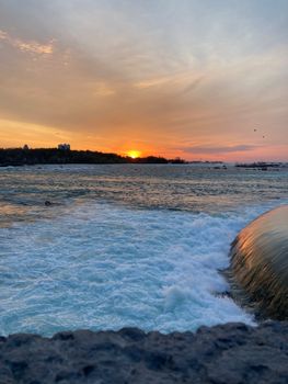 Capture the tranquility of a sunset view over Niagara Falls, blending vibrant skies and splashing water.