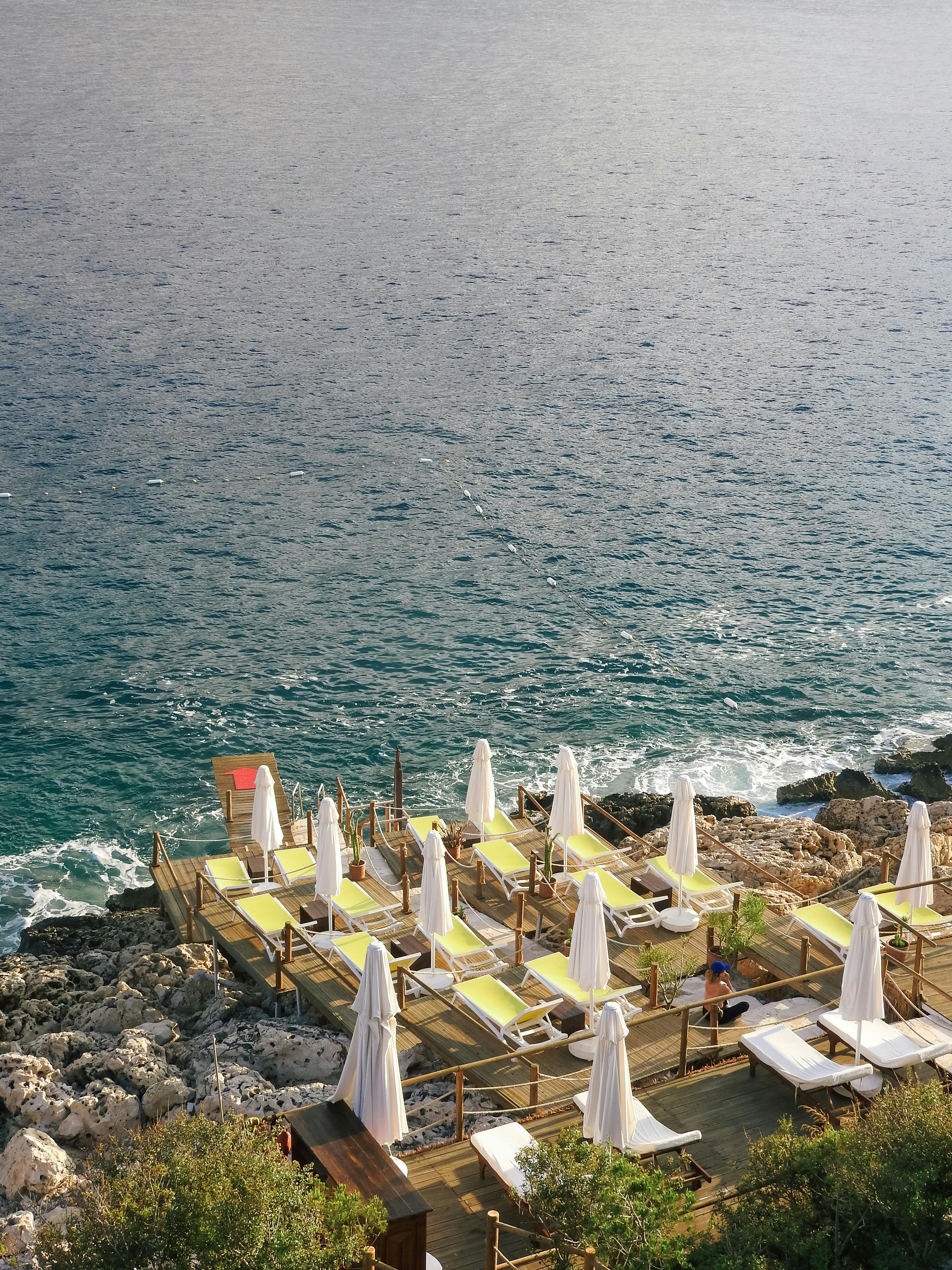 A serene seaside deck with sun loungers overlooking the rocky coast in Antalya, Türkiye.