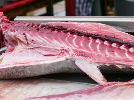 Close-up of a freshly sliced tuna fish fillet showing its red and white meat at the market.