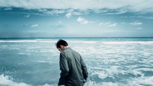 Free A man stands pensively by the ocean at Can Picafort, Mallorca, under a blue sky. Stock Photo