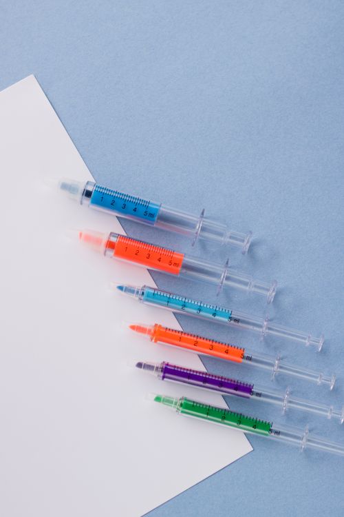 Free Creative display of colorful syringe pens against a blue backdrop. Stock Photo