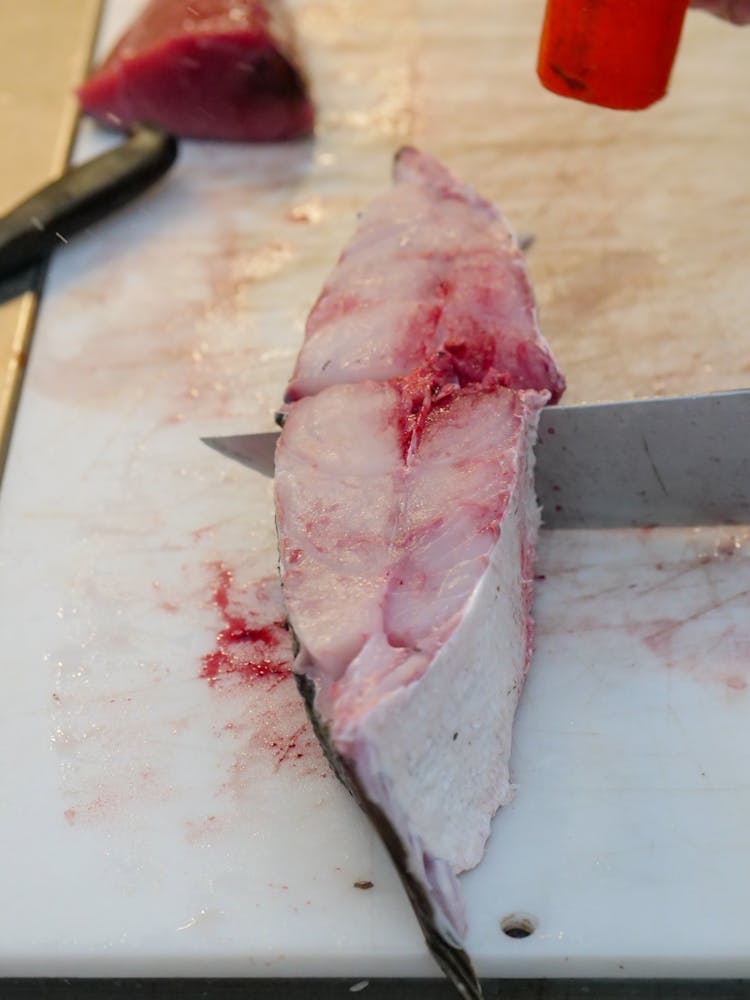 A Person Slicing A Raw Fish Meat