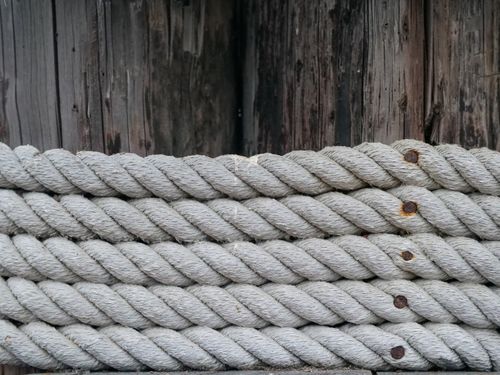 Free Detailed view of coiled nautical ropes against a rustic wooden background, emphasizing texture. Stock Photo