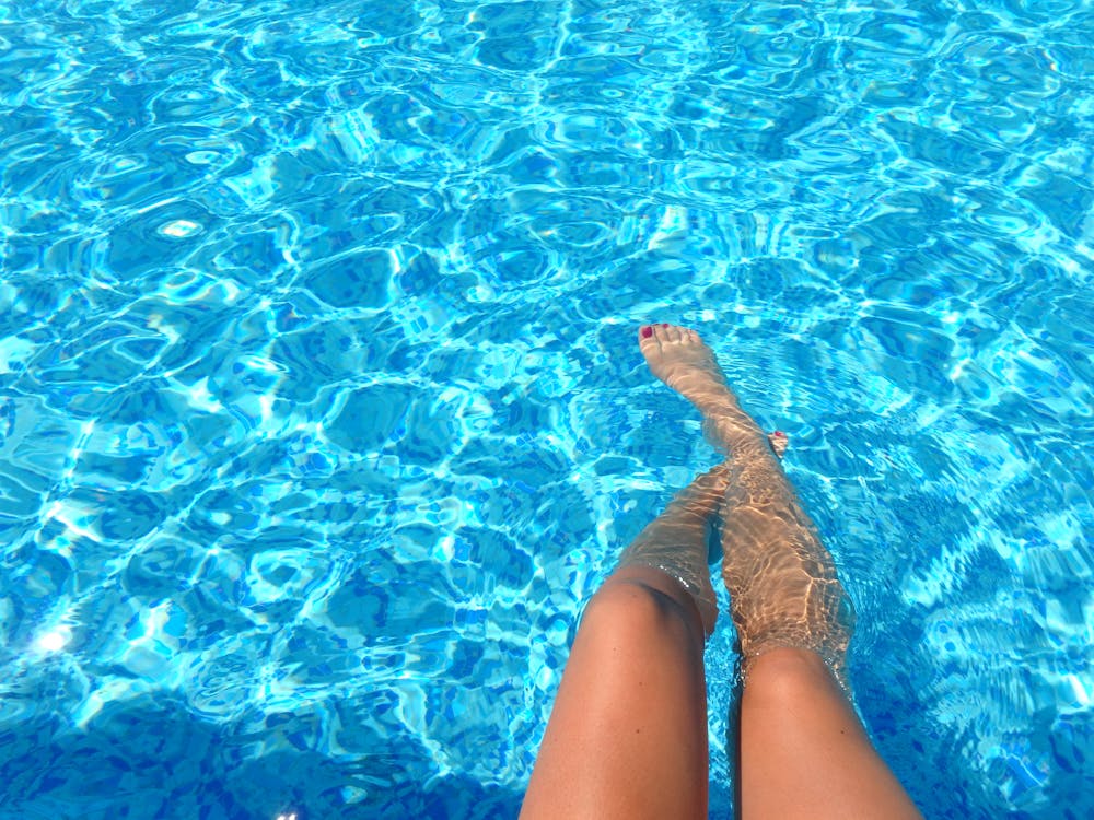 A girl soaking her legs in the swimming pool