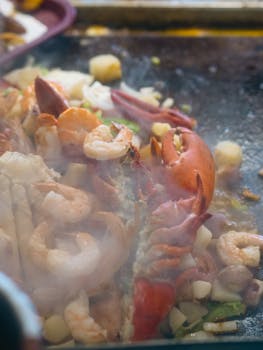 A delicious assortment of steaming seafood including lobster on a hot grill.