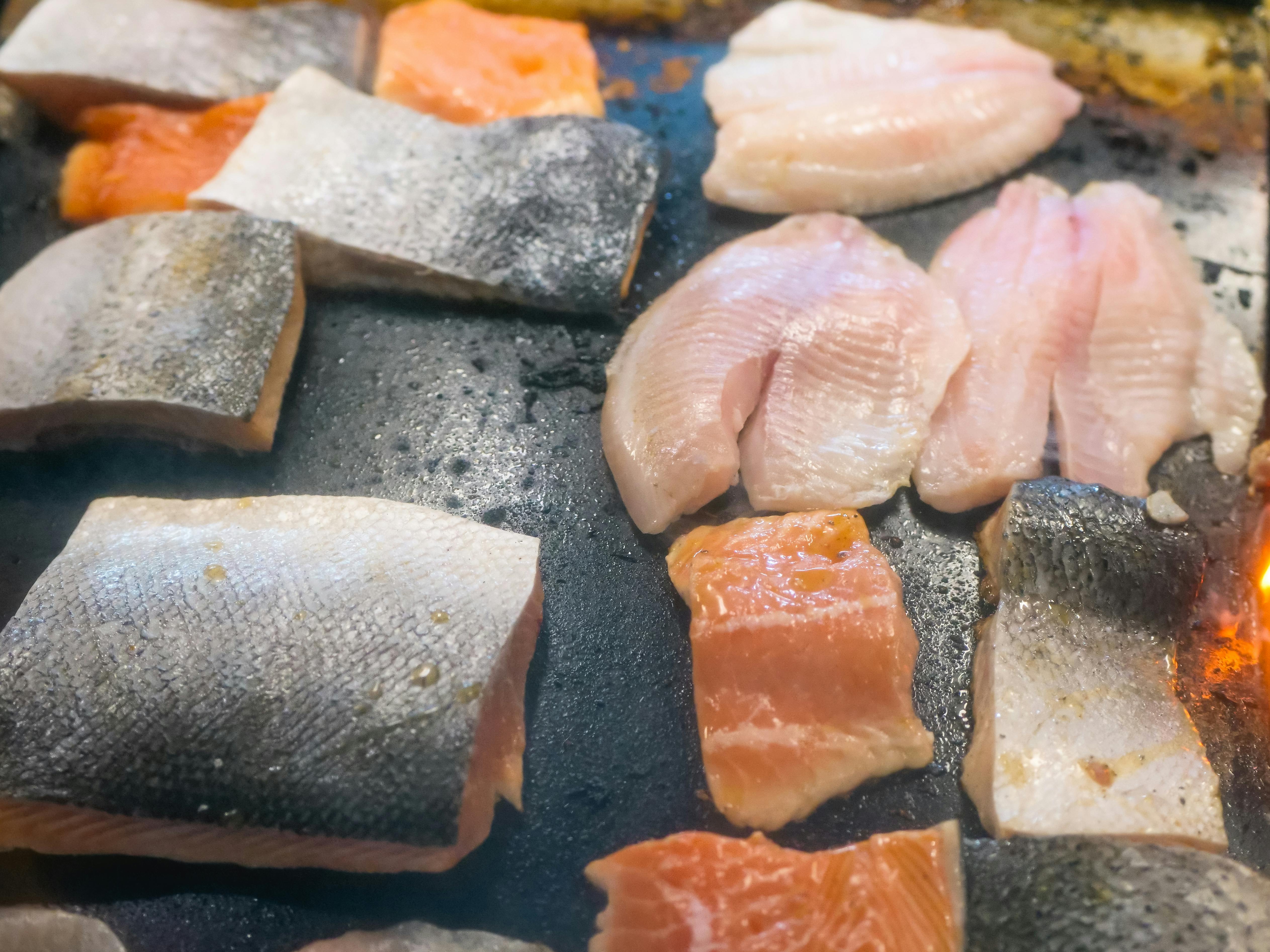 a selection of fresh fish fillets on a griddle
