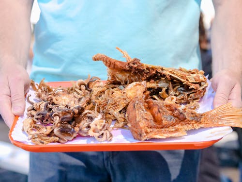 Man in Blue T-Shirt Holding Plate with Fried Seafood