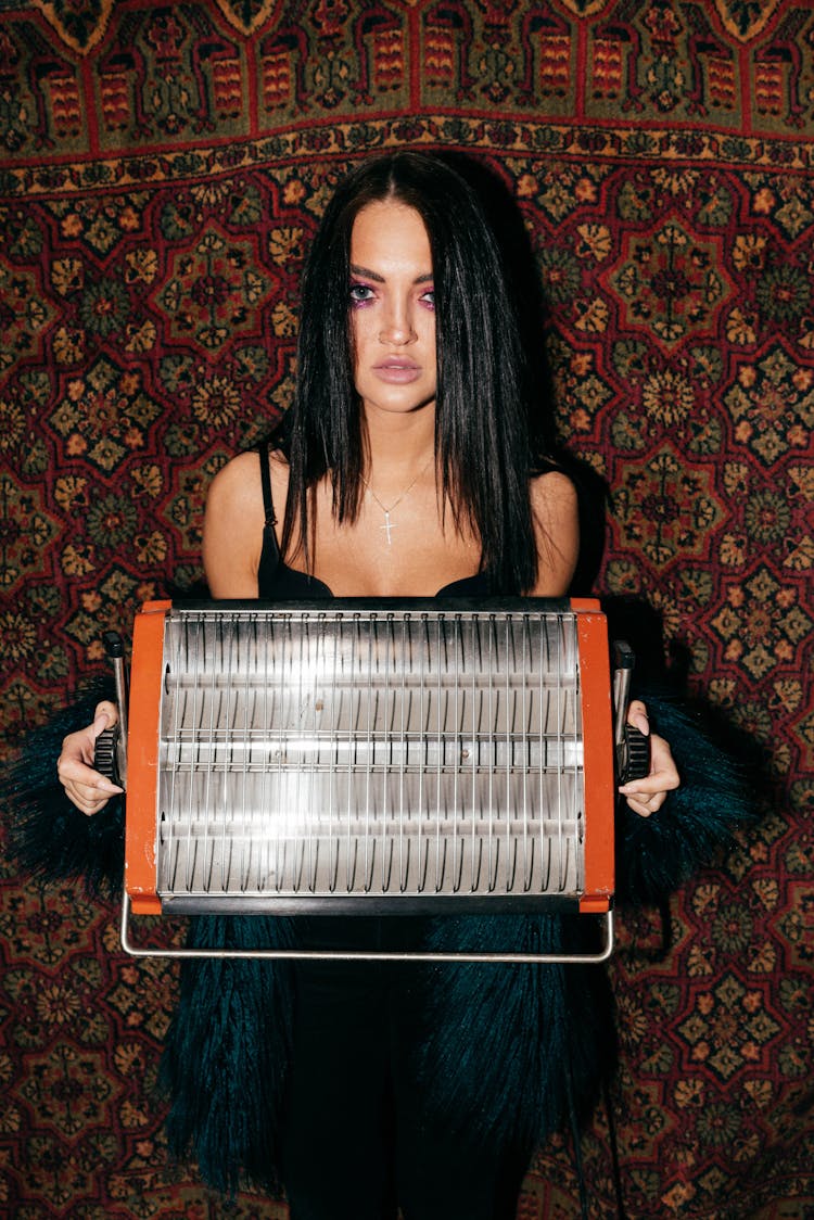 Woman Standing By A Rug Holding A Space Heater