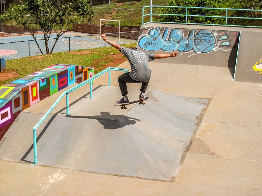 A skateboarder performs tricks on a ramp at an outdoor skatepark in Guarulhos, Brazil, showcasing skill and agility.