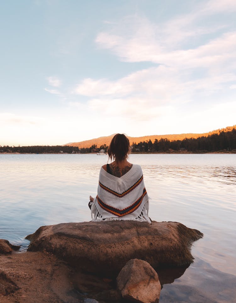 Back View Of A Woman Meditating By A Lake