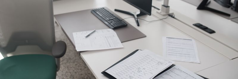 A clean and organized office desk with documents, a computer, and chair in a modern workspace.