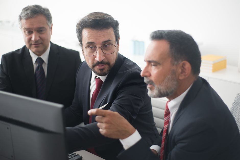 Tres hombres en una reunión corporativa discutiendo un proyecto en una oficina moderna.