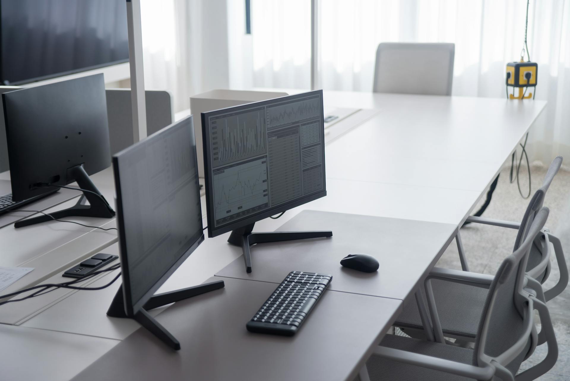 A clean and modern office desk with dual monitors and ergonomic chairs, ideal for productivity.