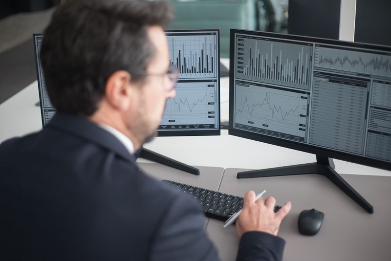 Office manager cross-checking numbers between two separate computer screens