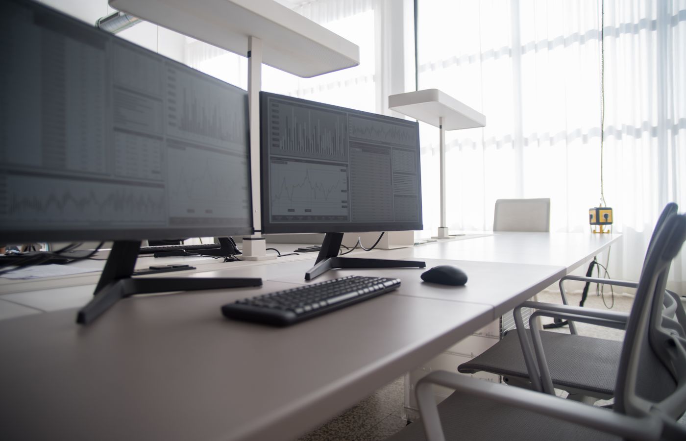 Stylish contemporary office featuring multiple computer monitors and ergonomic chairs.