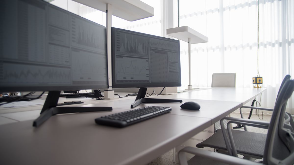 A clean two-monitor bookkeeping workspace with an organized keyboard and desk setup