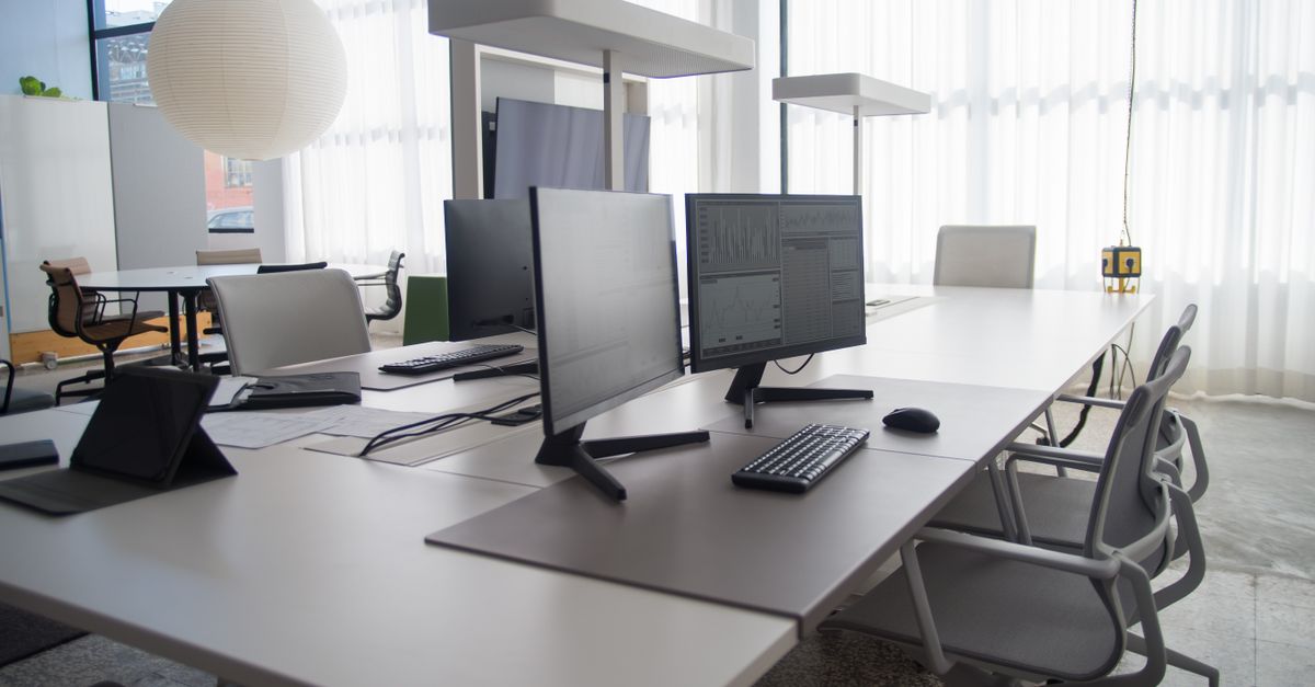 Spacious modern office featuring multiple computers, chairs, and collaborative workstations in natural light.