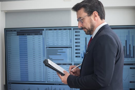 Businessman in a suit analyzing data analytics on large screens, taking notes.
