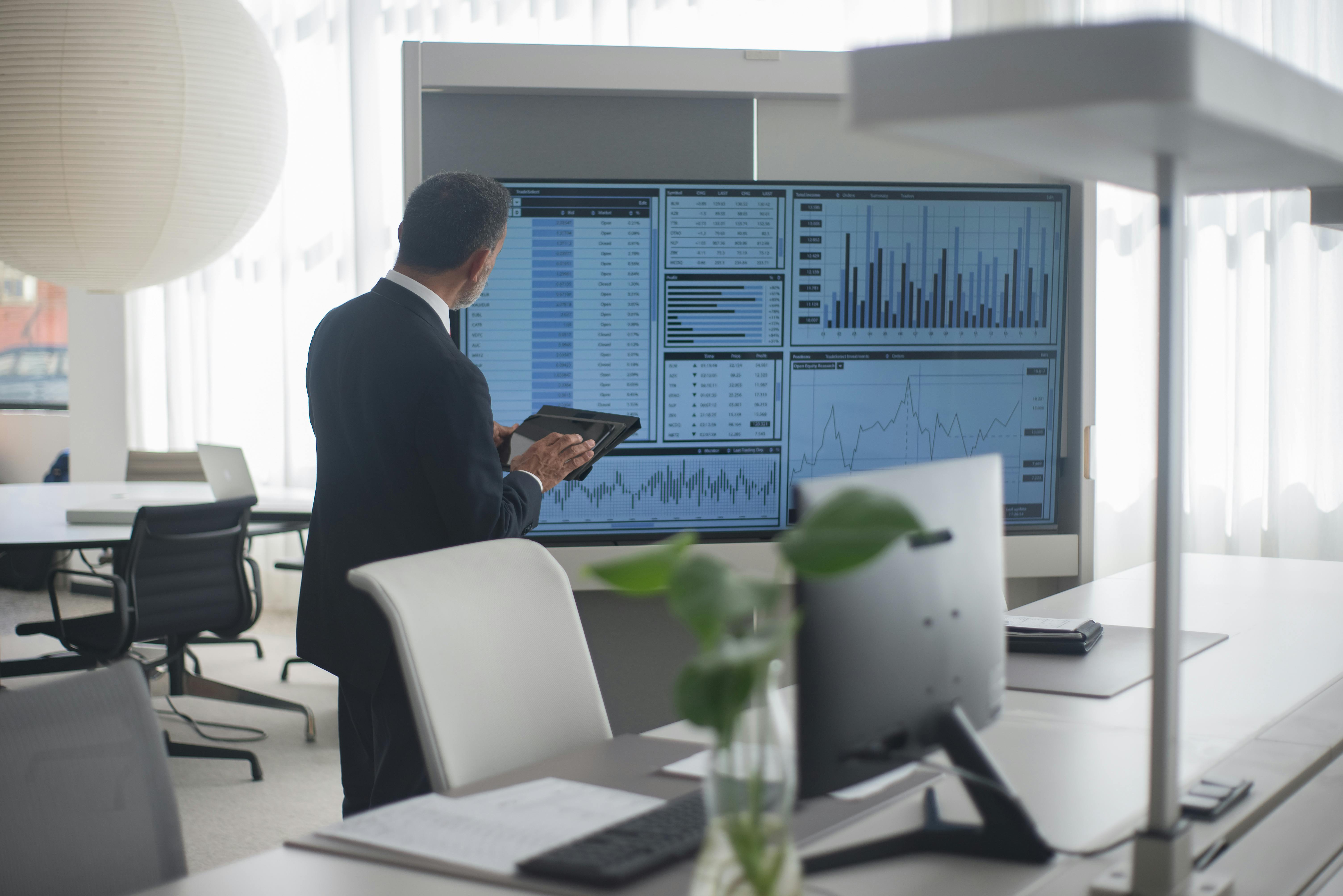 man looking at a screen with stock market data