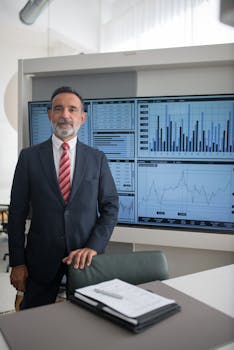 Confident businessman in office with data charts, analysis, and growth graphs on screen.